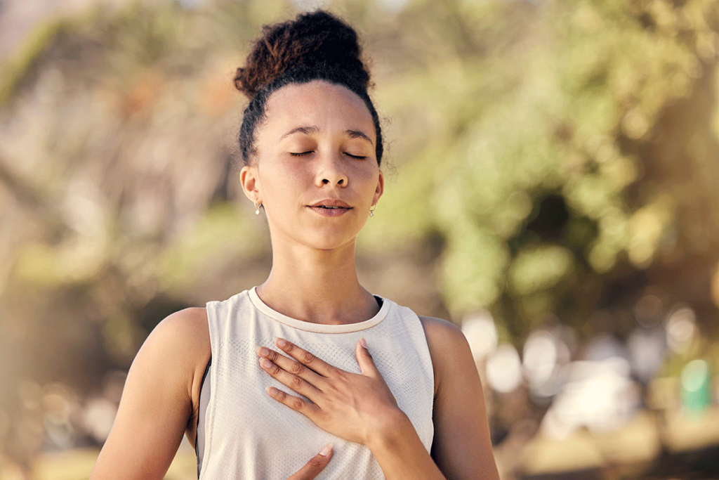 woman is outside with her eyes closed and hand to her heart practicing acceptance in recovery from addiction