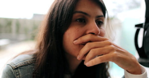 woman holds her hand to her mouth while wondering can you smoke cigarettes in rehab