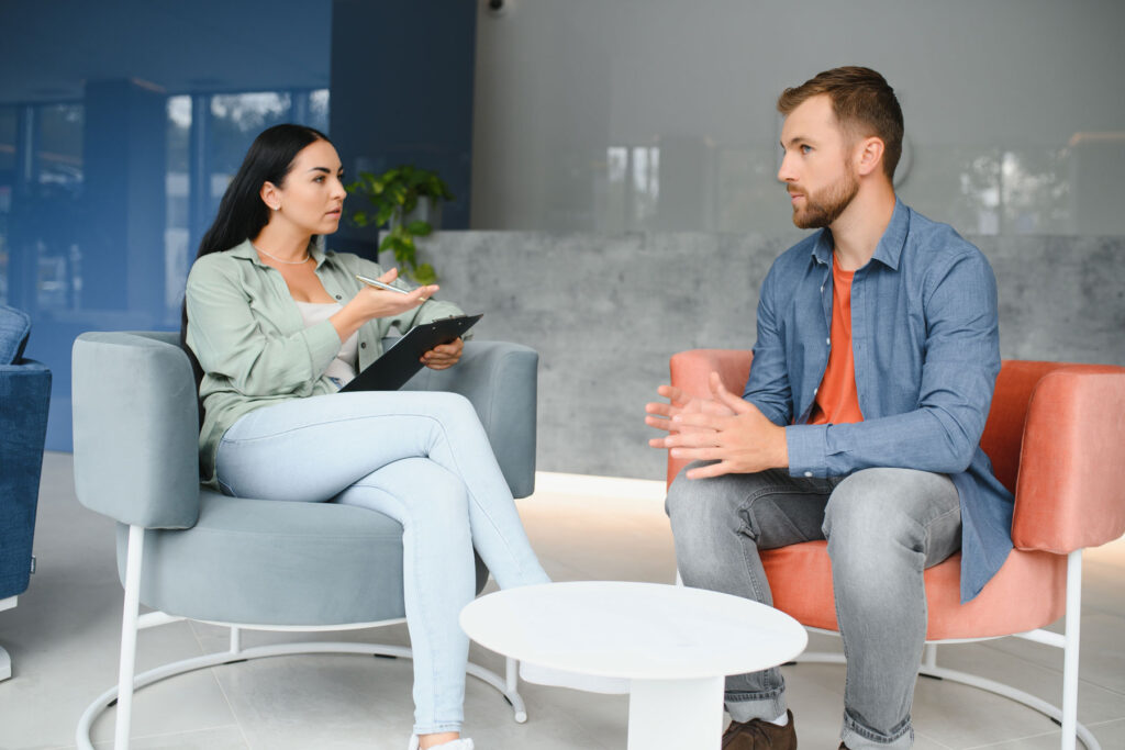 two people sit together in chairs and discuss treating bipolar disorder and addiction