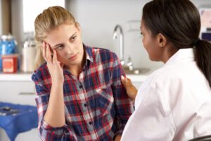 a blond woman sits with her therapist discussing the benefits of residential treatment