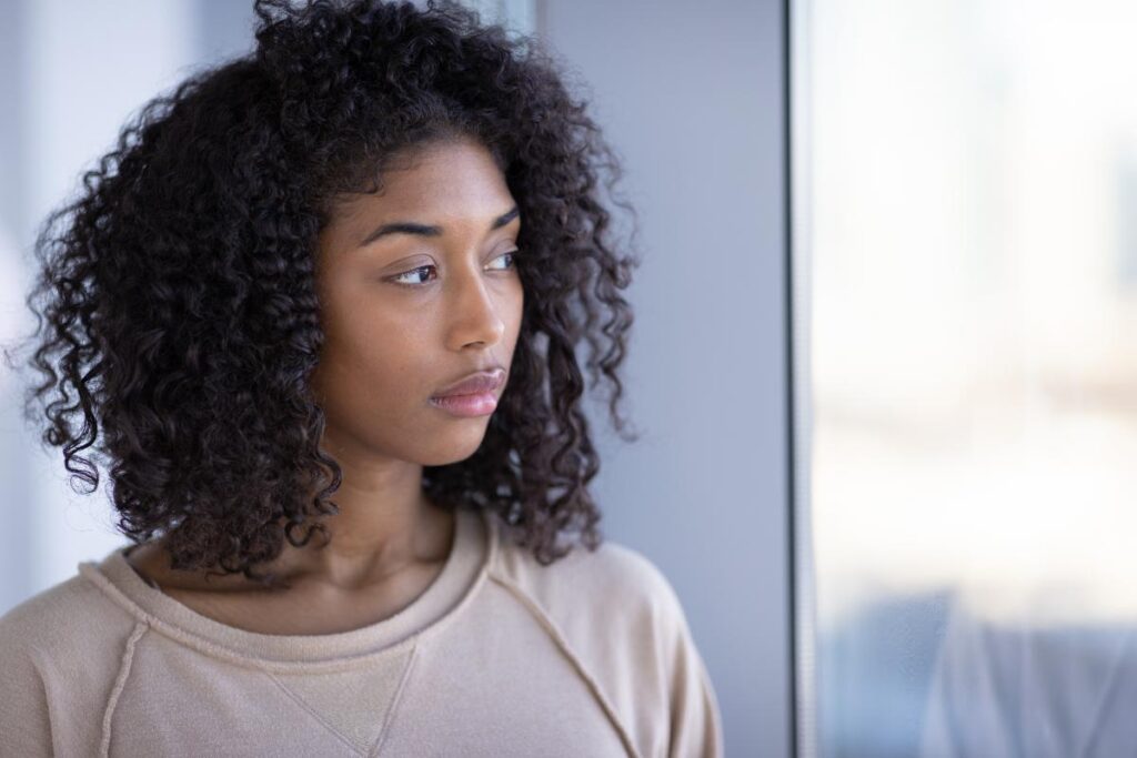 woman with curly hair looks off into the distance thinking about addiction replacement