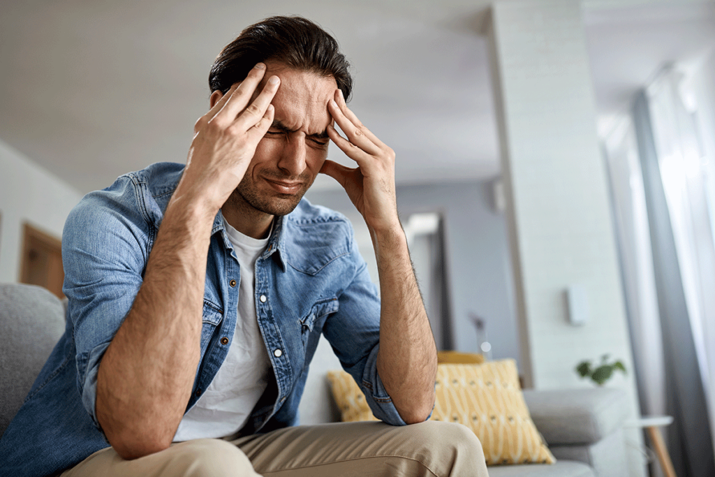 man enduring alcohol withdrawal treatment at home is in pain and puts his hands to his temples