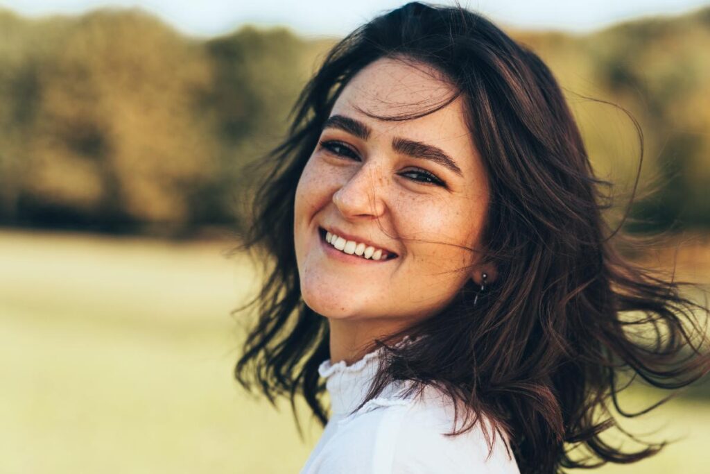 a woman with brown hair is outdoors and smiles while having her question about what is transitional living answered