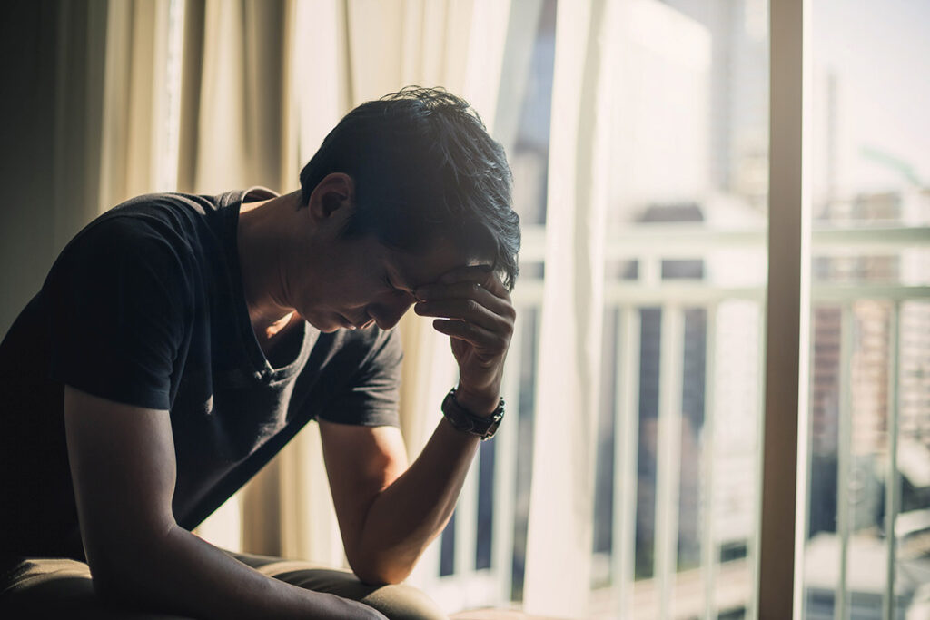 an upset person sits in the dark leaning over and holding his hand to his forehead struggling with some facts about ptsd