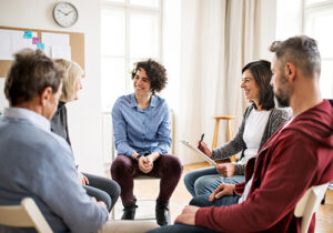 a group of people sit and participate in group therapy in their prescription drug addiction treatment programs
