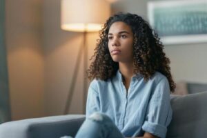 a woman with curly hair sits on a couch in her motivational interviewing therapy session