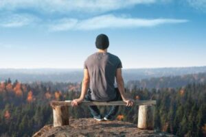 a person sits on a bench overlooking a valley of trees and wonders about relapse prevention therapy