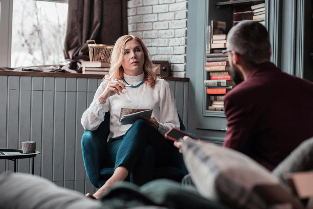 a therapist sits in a chair and answers her patients question about what is a partial hospitalization program