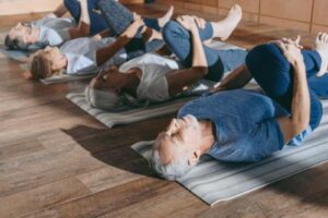 four people lay on the ground on yoga pats and practice yoga therapy