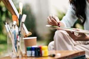 a person sits outsides and paints in their art therapy program