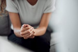 a person leans forward while sitting on a couch and holds their hands in dialectical behavior therapy