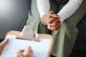 specialist holds clipboard while a patient sits across holding their hands in their painkiller addiction treatment 