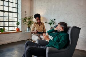 a man sits in a chair while talking to a therapist and asking what is experiential therapy