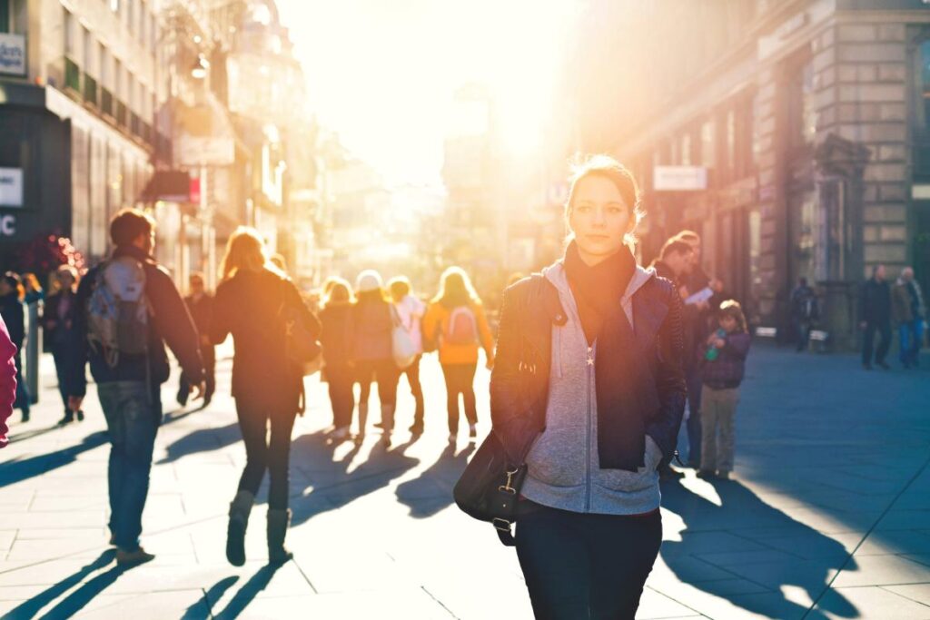 a woman stands outside on a street with other people behind her while she thinks about the opioid epidemic