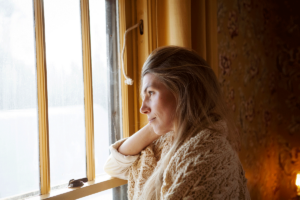 mature woman stares out her window troubled by addressing the stigma of addiciton in her community