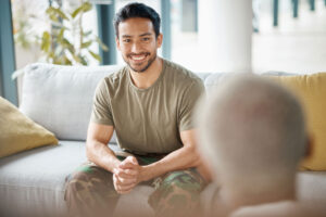 a smiling man in a military uniform sits on a couch while talking to a therapist about tricare for retired military