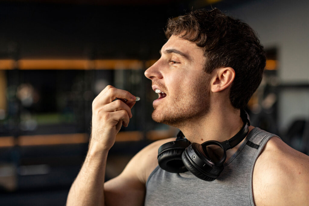 a man wearing headphones around his neck is putting a pill in his mouth ad wonders is adderall addictive