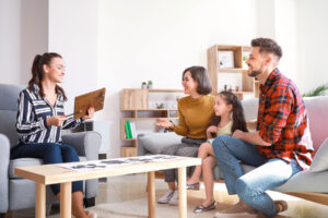 a family sits together on a couch while a therapy sits on a couch near them discussing family therapy techniques