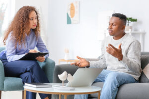 a man sits and talks to a therapist in his individual therapy session 