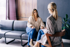 a woman sits on the couch while discussing with her therapist about individual counseling and its benefits on her recovery